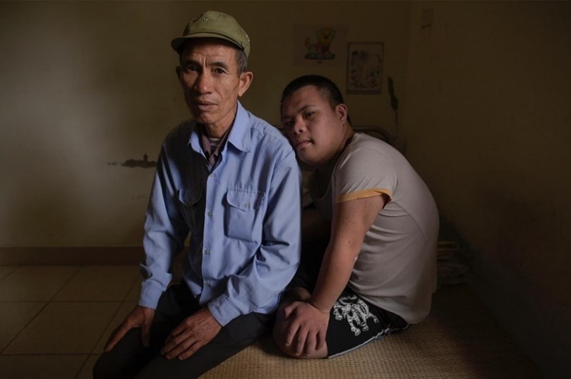 Former soldier Nguyen Hong Phuc, 63, sits on the bed with his son Nguyen Dinh Loc, 20
